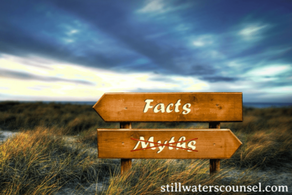 A wooden sign with arrows points in opposite directions, labeled Facts and Myths, set against a grassy landscape under a cloudy sky.