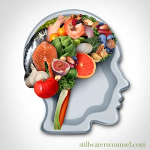 Silhouette of a human head filled with various healthy foods, including fish, vegetables, fruits, and nuts, symbolizing nutrition for brain health. Website text stillwaterscounsel.com is present.