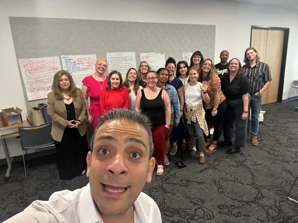 Group of people posing for a cheerful selfie in a conference room.